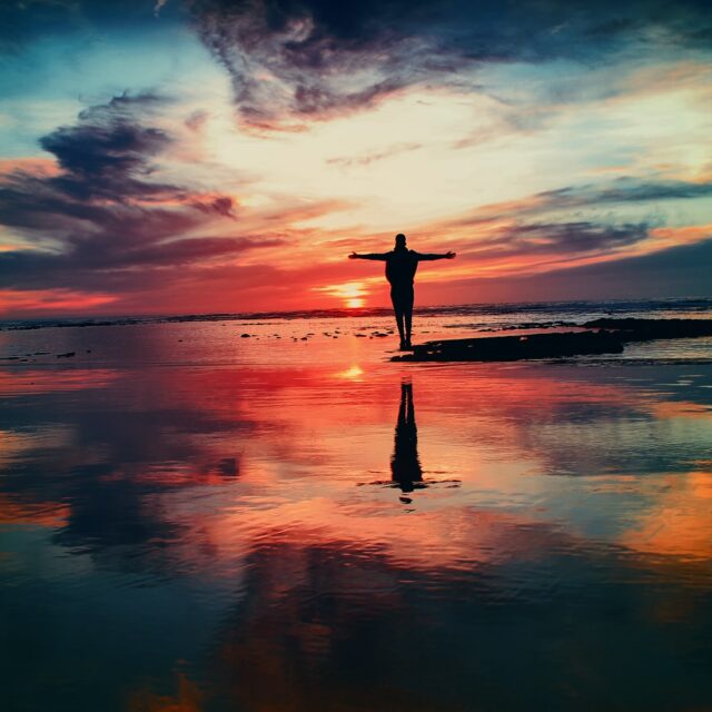 Mensch steht vor Sonnenuntergang am Meer